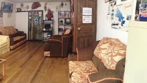 A living room with a beige sofa, a wooden coffee table, and a patterned armchair. - Natys guest house (Cusco)