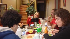 A group of people sitting around a table with various food items and drinks. - Natys guest house (Cusco)