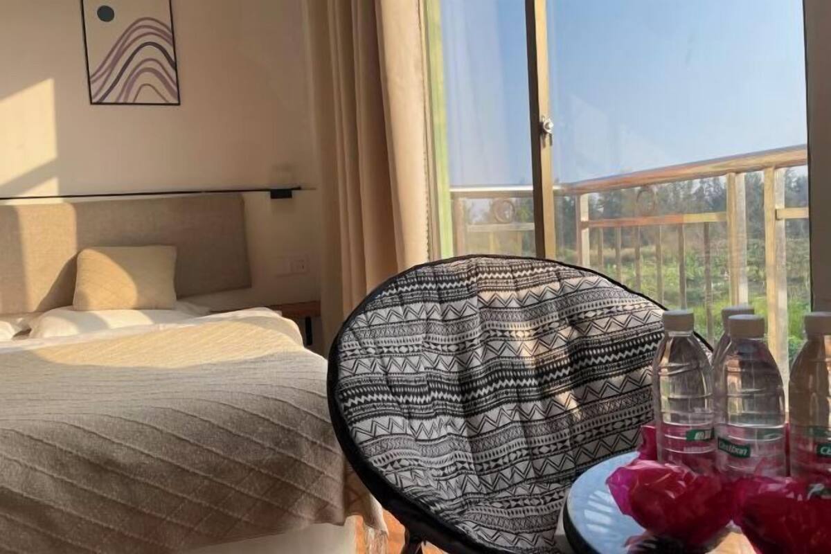 A hotel room with a bed, a chair, and a table with water bottles.