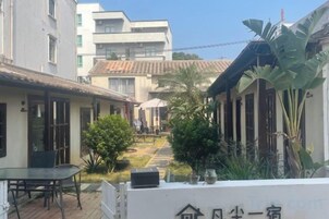 Um pátio com um caminho, uma mesa e cadeiras, e uma placa escrita em caracteres chineses.