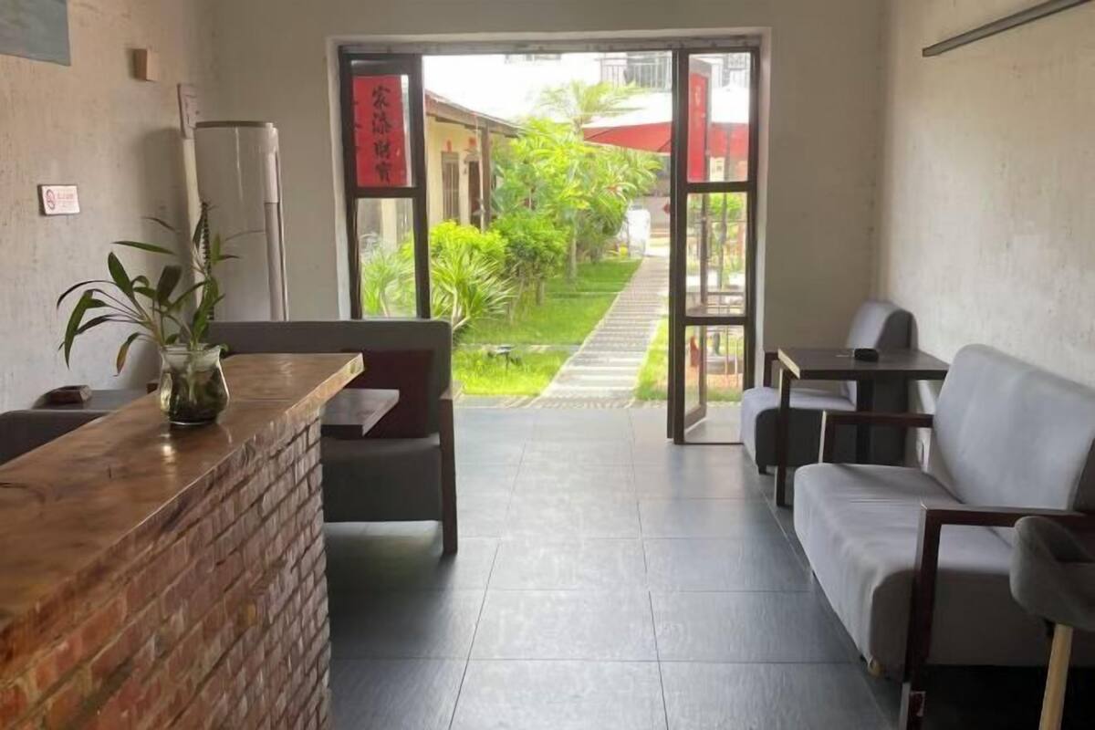 A reception area with a brick counter, a potted plant, a sofa, and a table.