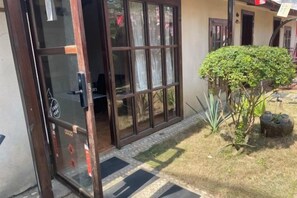 A residential property with a sliding glass door entrance, a small garden with a shrub, and a tiled pathway. - Beihai Weizhou Xiaodeng Yujiale (Beihai)