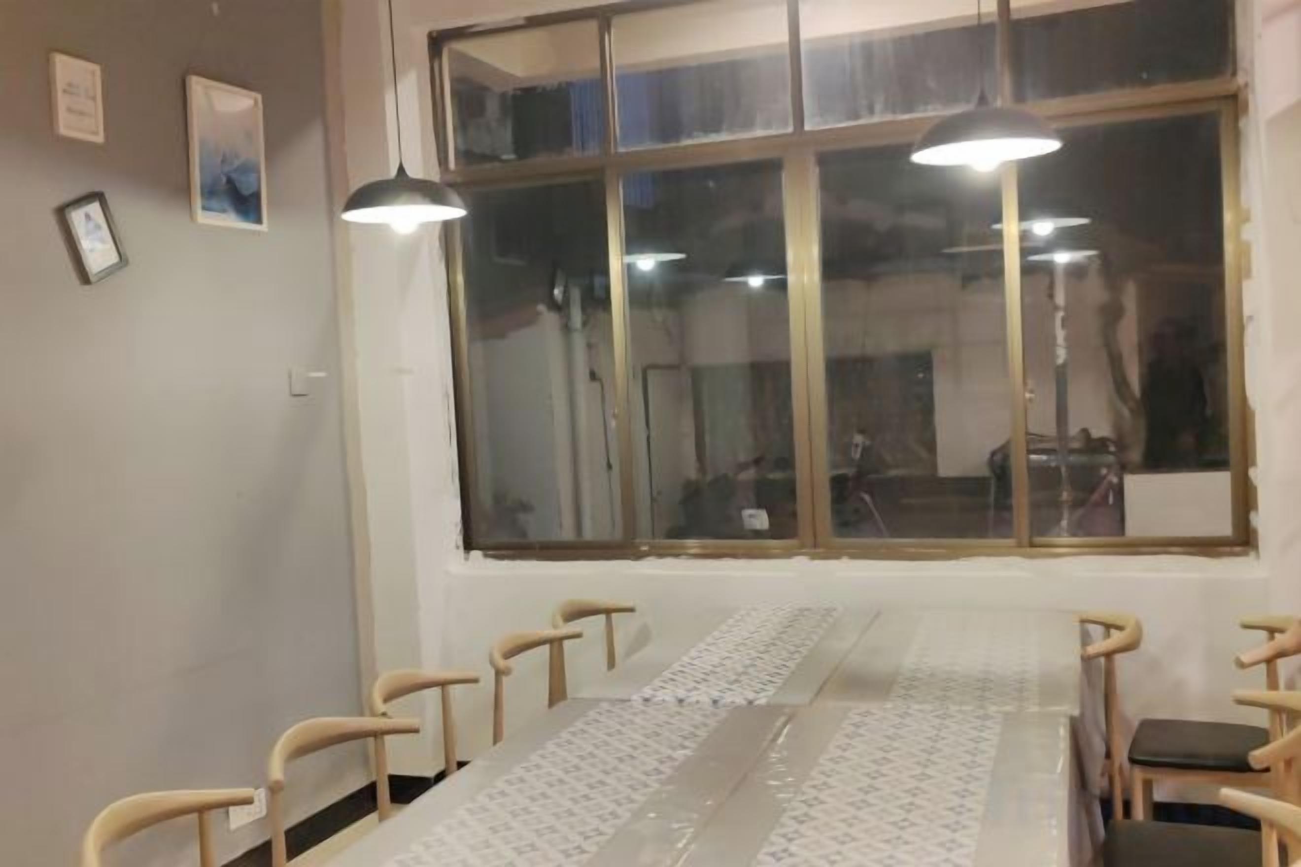 Un salón de conferencias con una larga mesa, sillas y dos lámparas colgantes.