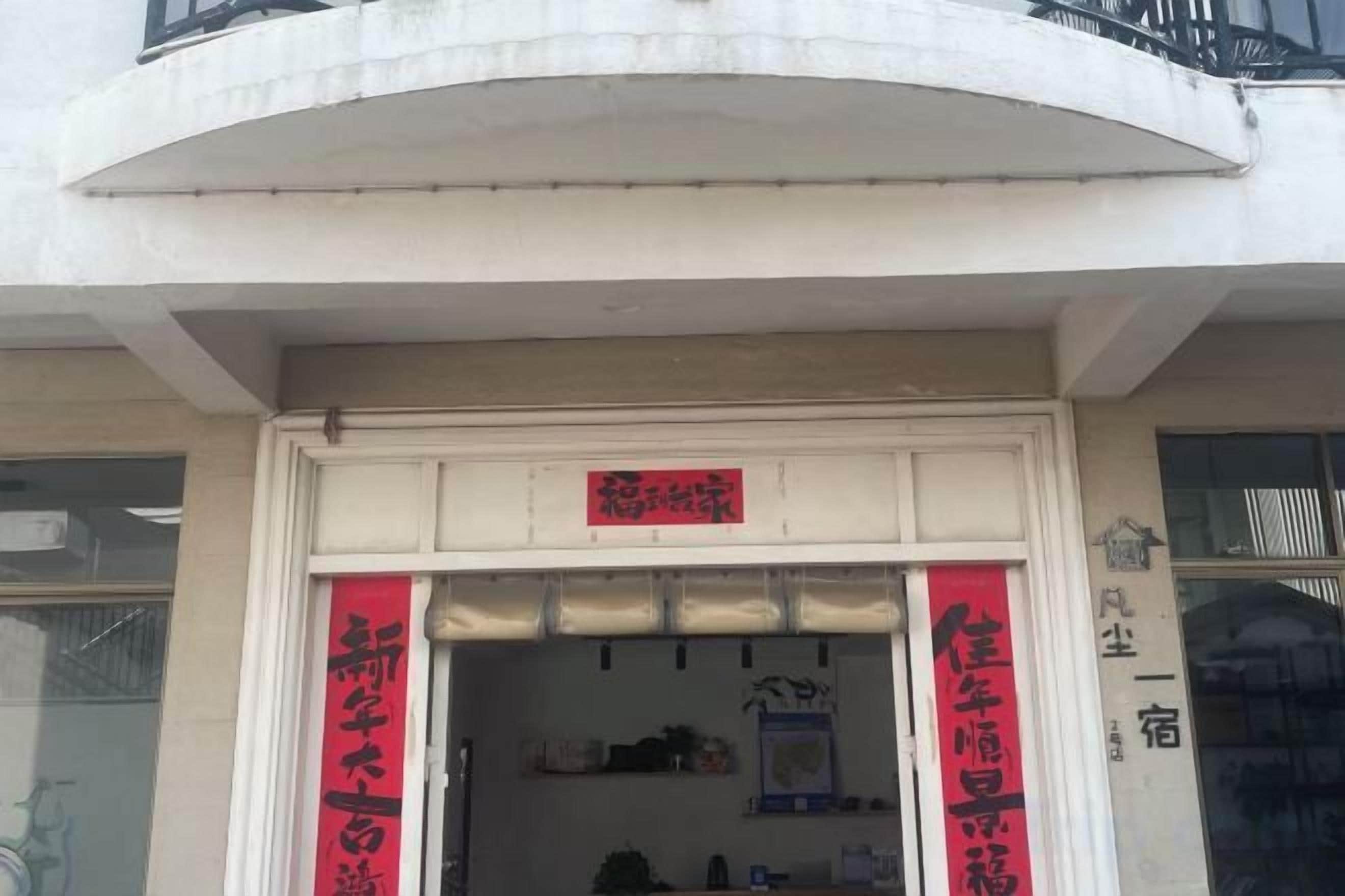 Entrada de un edificio con un cartel y dos lonas verticales.