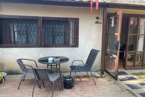 An outdoor patio with a round table and four chairs, a small trash bin, and a door leading to an interior space. - Beihai Weizhou Xiaodeng Yujiale (Beihai)