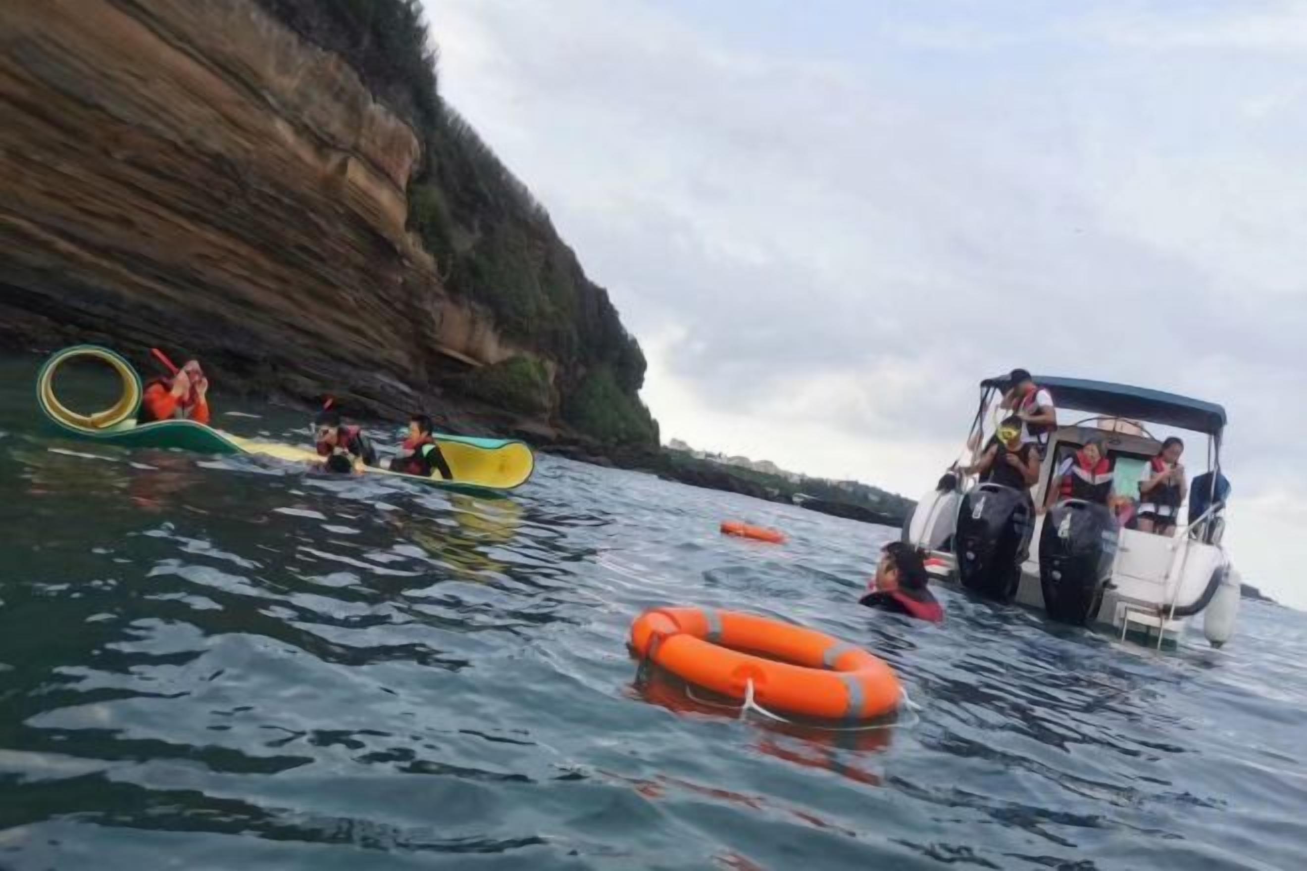A boat with people on a body of water, surrounded by cliffs.