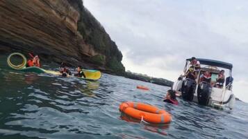 A boat with people on a body of water, surrounded by cliffs.