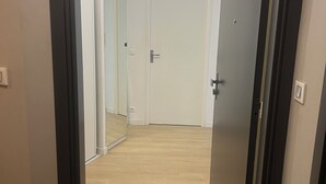 Un couloir avec un plancher en bois, des murs blancs et une porte fermée au bout.