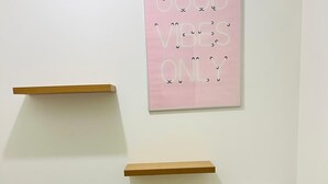 Une salle de bain avec des toilettes, une étagère au-dessus des toilettes et un panneau rose sur le mur.