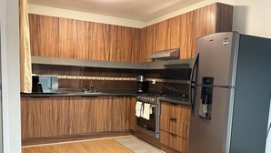 Eine moderne Küche mit Holzschnitzerei, einem Edelstahlkühlschrank und einem eingebauten Ofen.