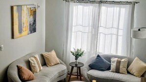 Ein Wohnzimmer mit zwei grauen Sofas, einem kleinen runden Tisch mit Kerzen und einem Gemälde an der Wand.