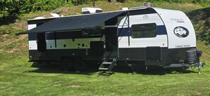 Ein Forest River Wohnmobil mit schwarzem Markisenaufbau, einer Rampe und einem Logo an der Seite.