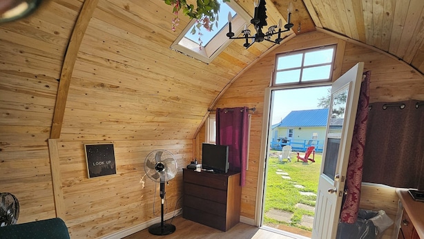 A cozy, wooden interior with a sofa, a TV, and a fan.