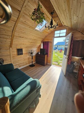 A cozy, wooden interior with a sofa, a TV, and a fan. - Parkview Cottages Resort (Kawartha Lakes)