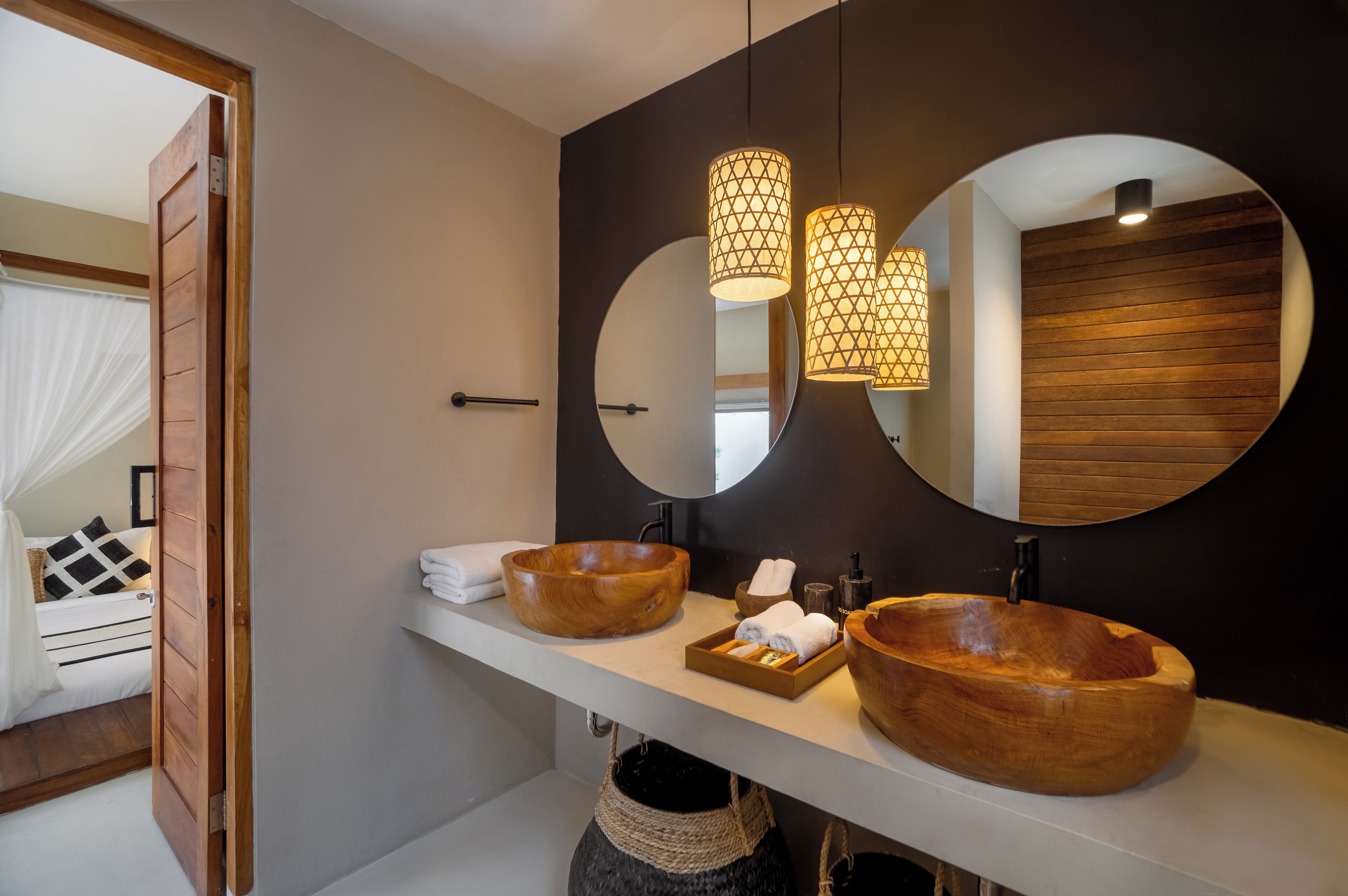 Un baño moderno con dos lavamanos de madera, un espejo grande y lámparas colgantes.