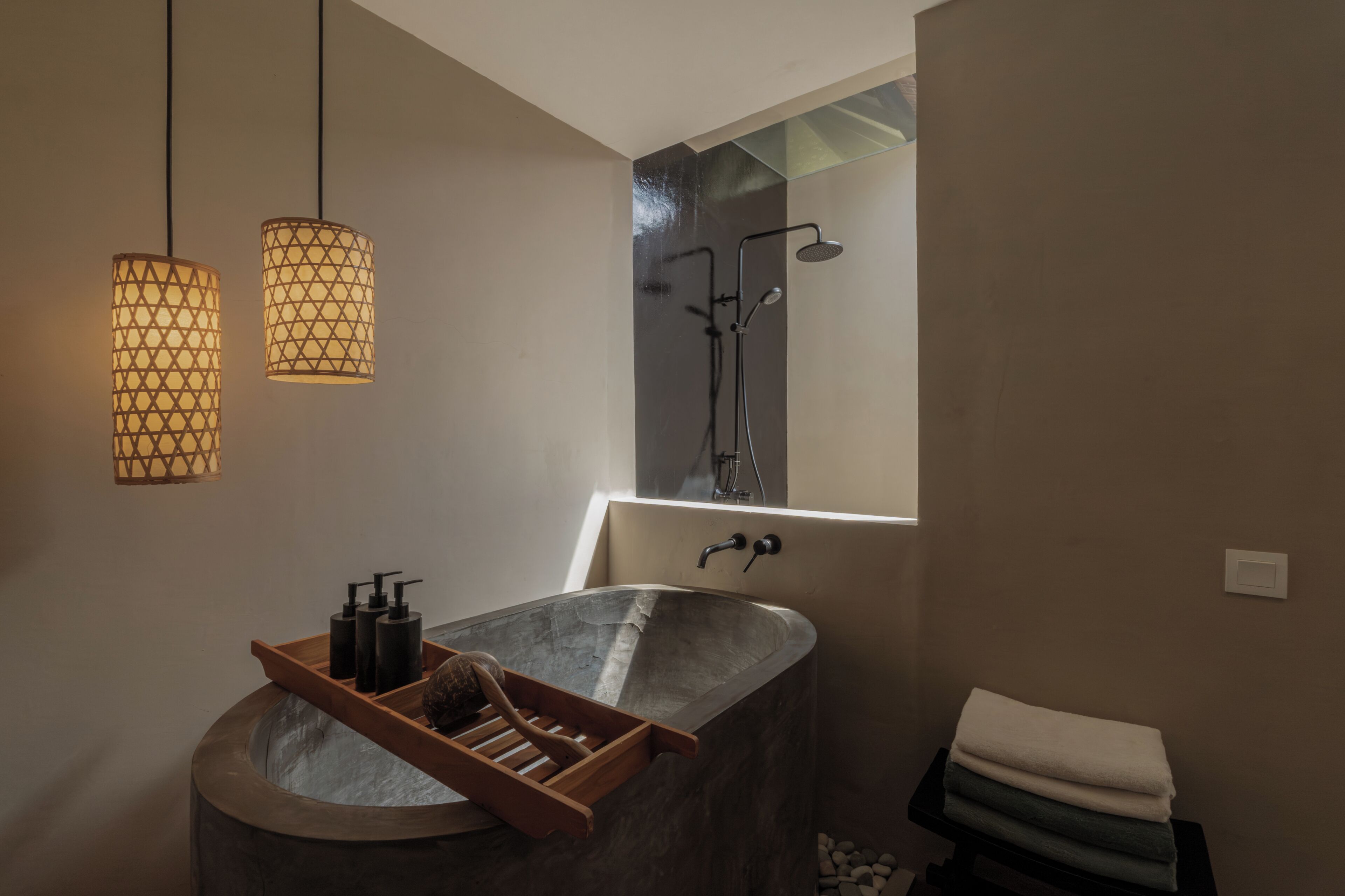 Een badkamer met een vrijstaand bad, een douche, hanglampen en een handdoekrek.