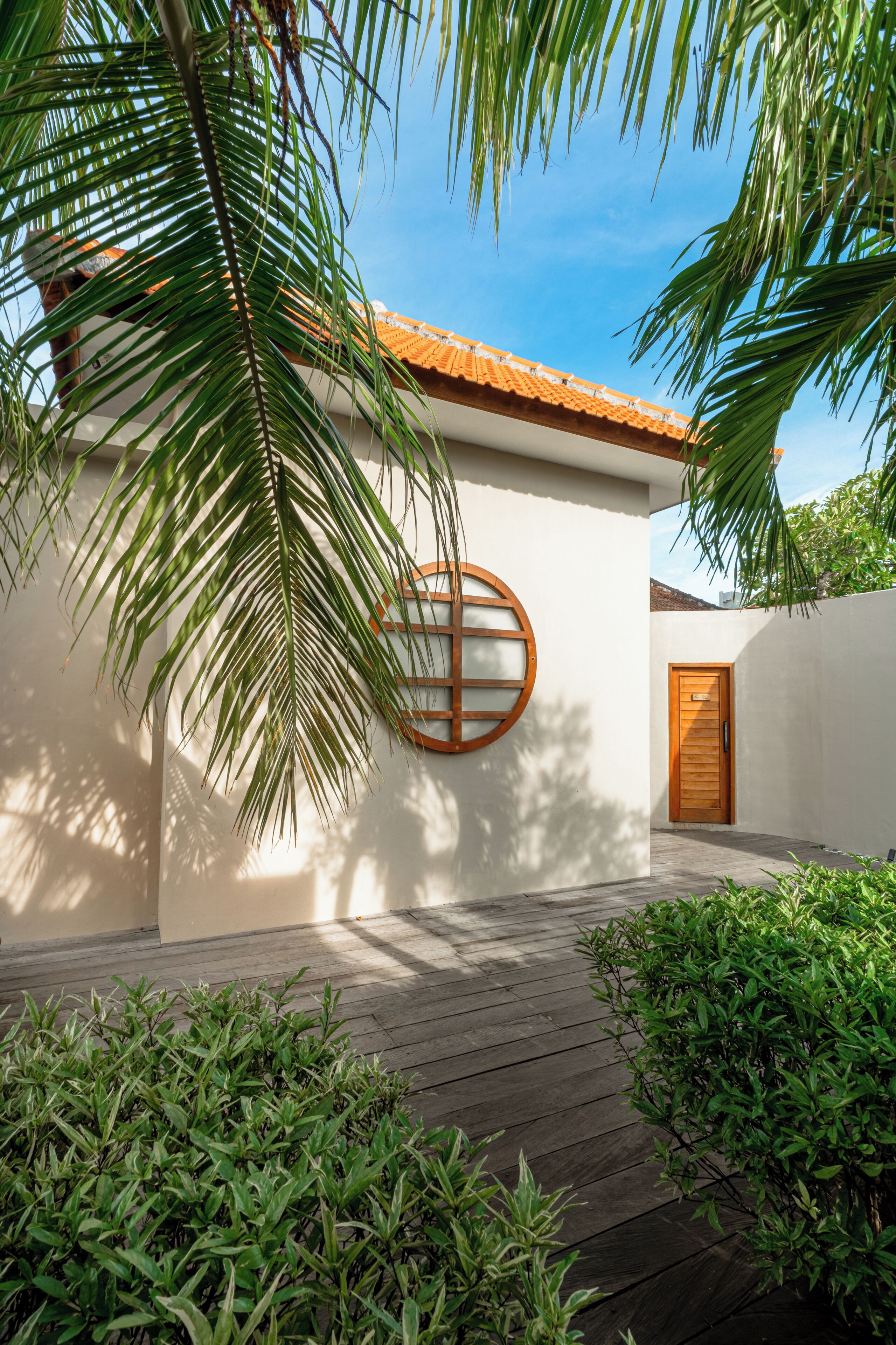 A building with a wooden door, a circular window, and a wooden deck.