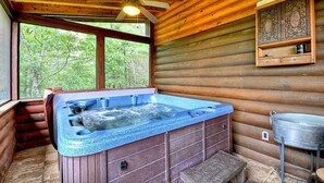 Eine Holzhütte mit Whirlpool, Deckenventilator und Spüle aus Metall.