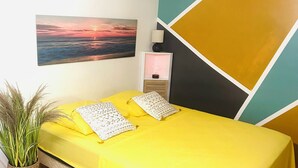A room with a bed, a nightstand, a lamp, a wall painting, and a potted plant. - Studio in a green setting 15 min from the Jarry industrial zone and 2 min from the rivers. (Petit-Bourg)