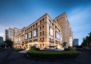 A large, multi-story building with a fountain in the center, surrounded by greenery. - Philosopher Hotel (Shanghai)