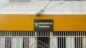 Un immeuble avec une enseigne indiquant « RÉSIDENTIEL BARBOSA » et une entrée fermée par un portail.
