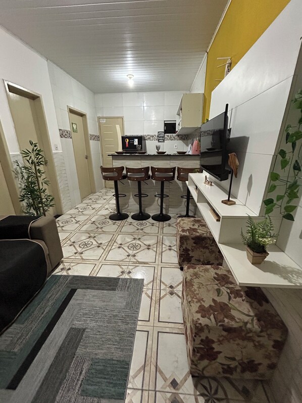 A compact living space with a kitchen area, a sofa, a coffee table, and a potted plant.