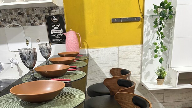 Un coin repas avec une table noire, des bols marron et un panneau en portugais.