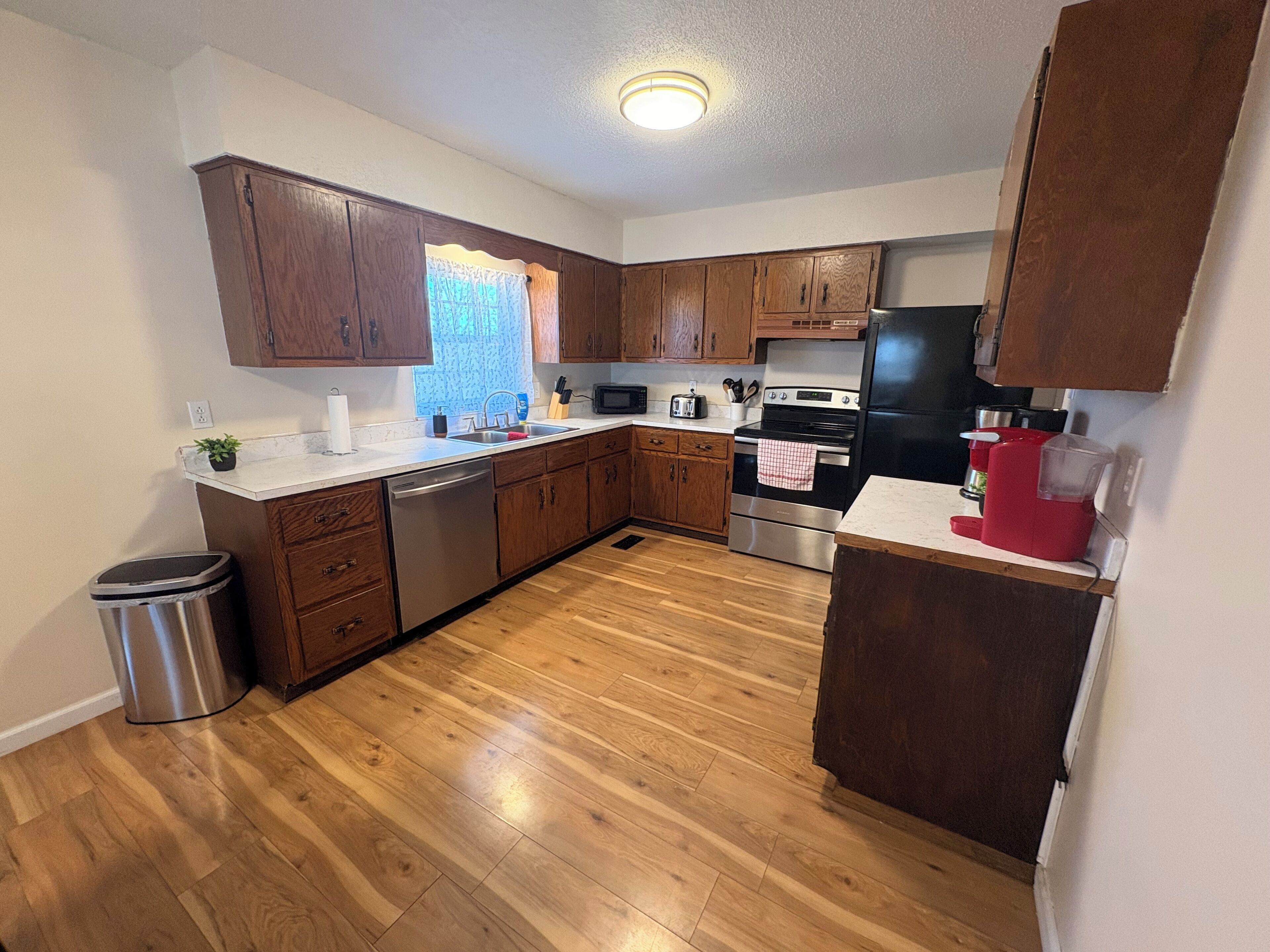 Une cuisine avec des meubles de rangement en bois, des appareils électroménagers en acier inoxydable et un plancher en bois.
