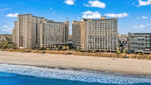 A beachfront hotel with multiple high-rise buildings, a sandy beach, and ocean waves. - Oceanfront Condo with Lazy River (North Myrtle Beach)