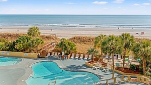 A beachfront resort with multiple swimming pools, palm trees, and a beach in the background. - Oceanfront Condo with Heated Pools (North Myrtle Beach)