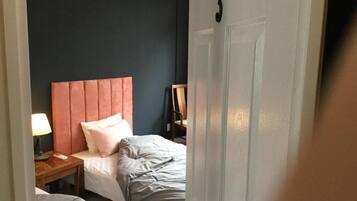 Une chambre d’hôtel avec deux lits, une table de chevet en bois avec une lampe et une porte dotée d’une poignée.