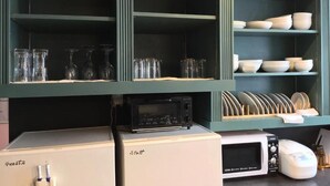 A kitchen with a white refrigerator, a microwave, and a toaster. There are shelves above holding glassware and dishes. - LANAIHOTEL & DORMITORY  (Naha)