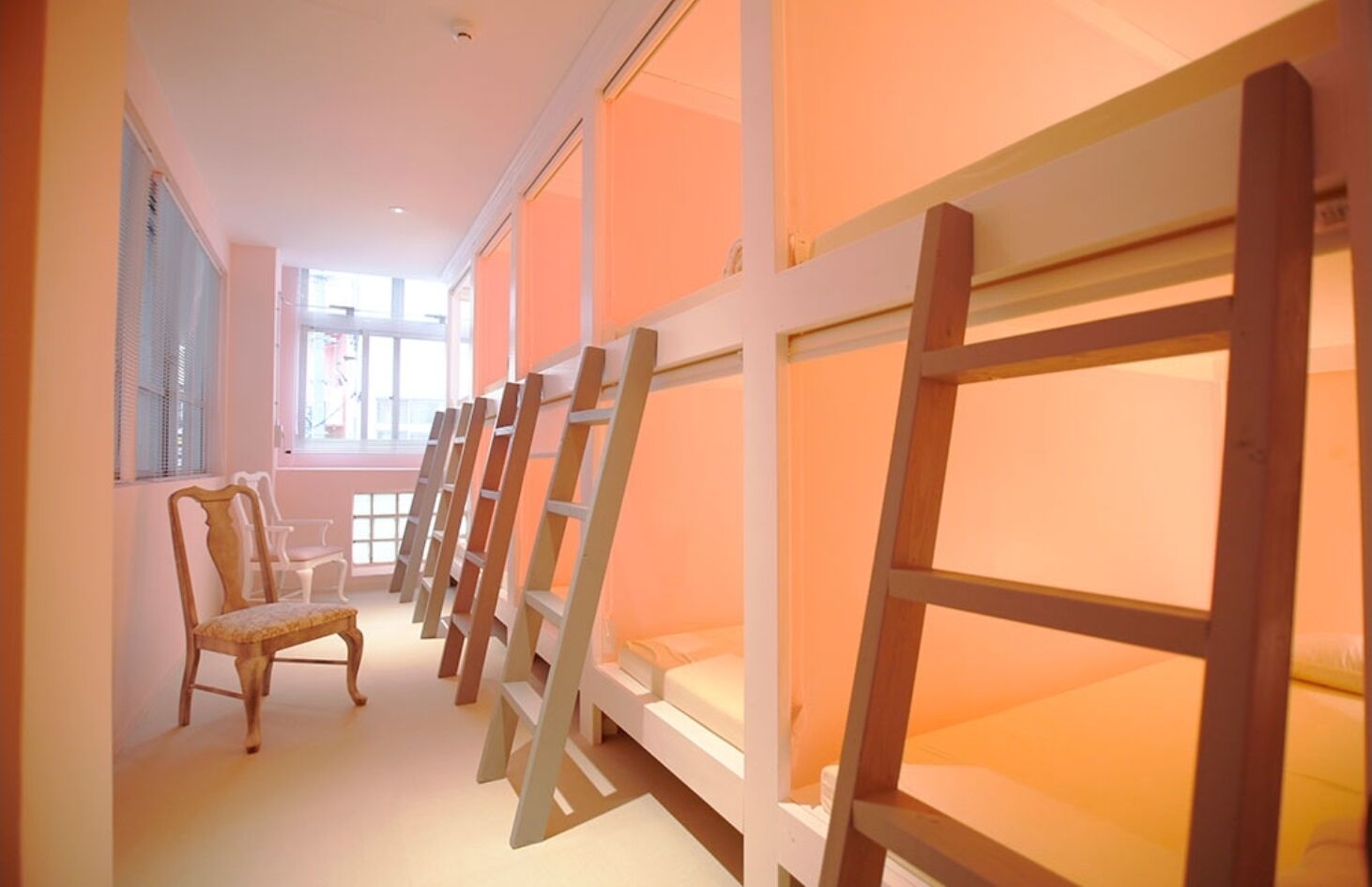 A hallway with bunk beds and a chair.