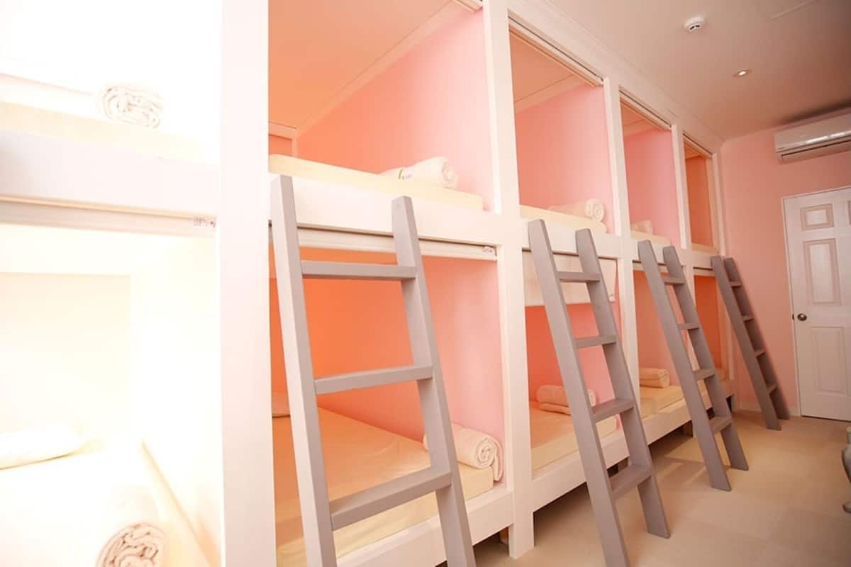 Bunk beds with ladders, a white door, and a pink wall.