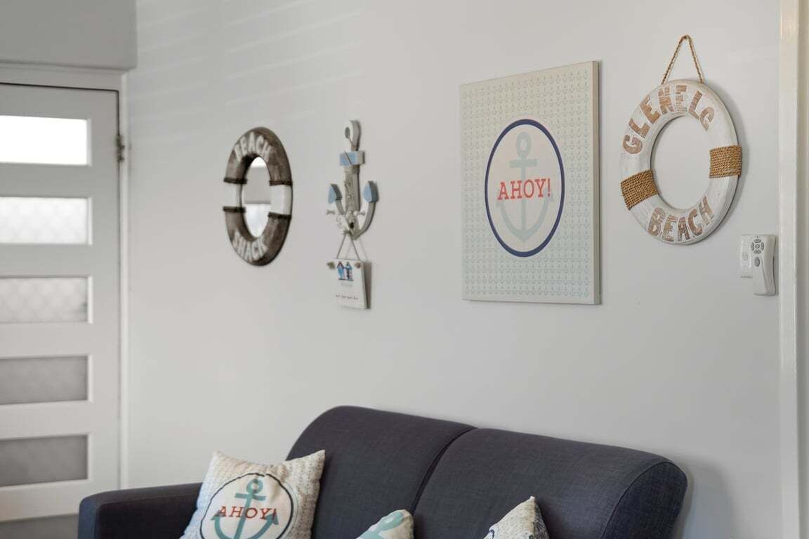 A living room with a dark-colored sofa and decorative wall art including circular and anchor-themed pieces.