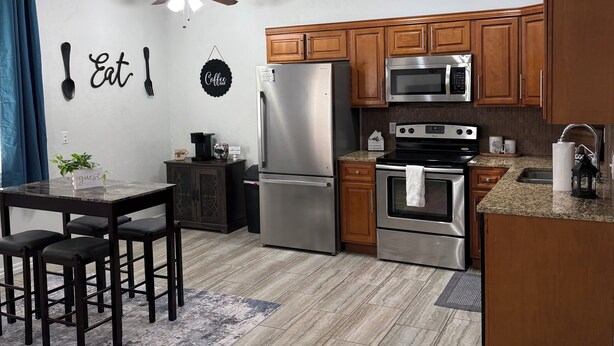 A modern kitchen with wooden cabinets, stainless steel appliances, and a dining area with a table and chairs.