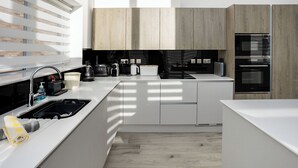 Een moderne keuken met een inbouwoven, een spoelbak en een koffiezetapparaat.