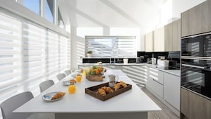 Een moderne keuken met een centraal eiland, witte kasten en een groot raam dat voor natuurlijk licht zorgt.