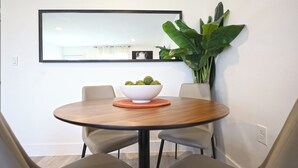 A dining area with a round table, two chairs, a bowl of fruit, and a large plant. - Cozy Downtown Dallas Urban Glow Retreat (Dallas)