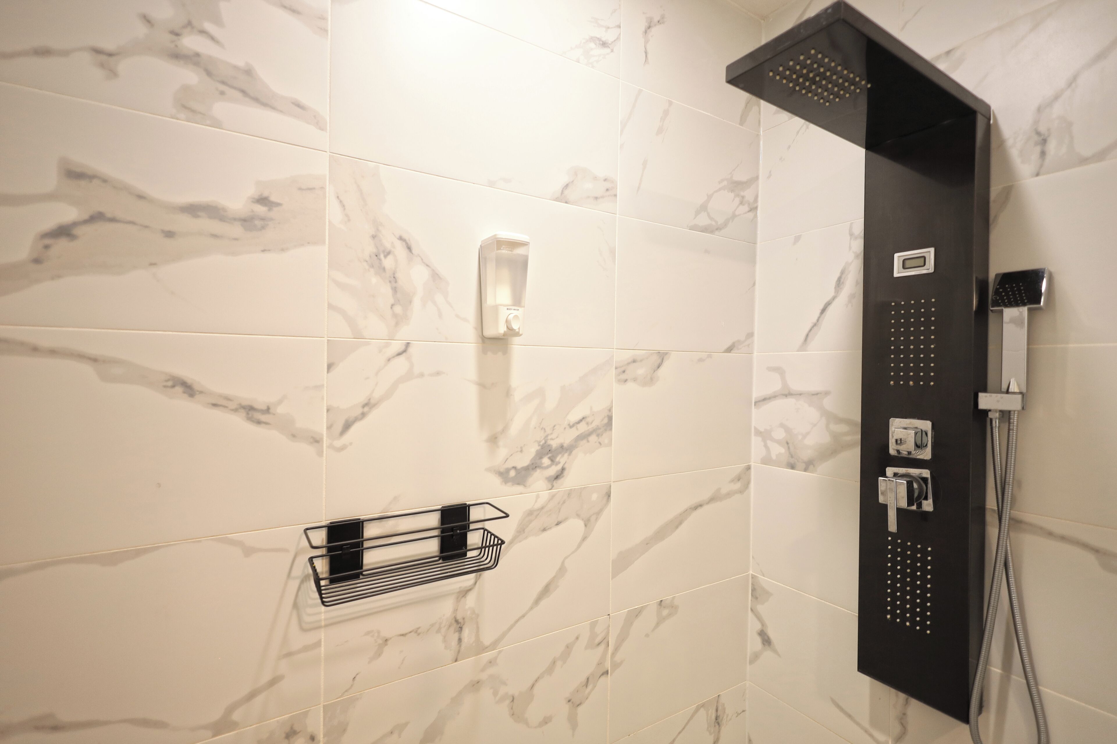 Une douche moderne dotée d’un panneau de commande, d’un pommeau de douche à main et d’un porte-serviettes.
