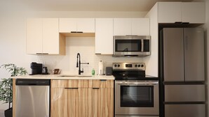 A modern kitchen with stainless steel appliances, wooden cabinets, and a built-in microwave. - Cozy Downtown Dallas Urban Glow Retreat (Dallas)