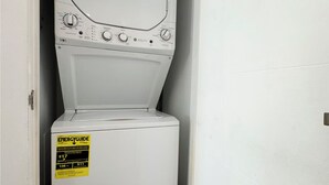 A compact, white front-loading washer and dryer unit with a yellow EnergyGuide sticker. - Cozy Downtown Dallas Urban Glow Retreat (Dallas)