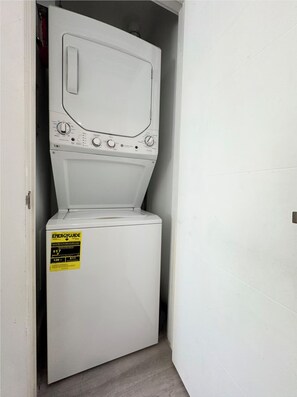 A compact, white front-loading washer and dryer unit with a yellow EnergyGuide sticker. - Cozy Downtown Dallas Urban Glow Retreat (Dallas)