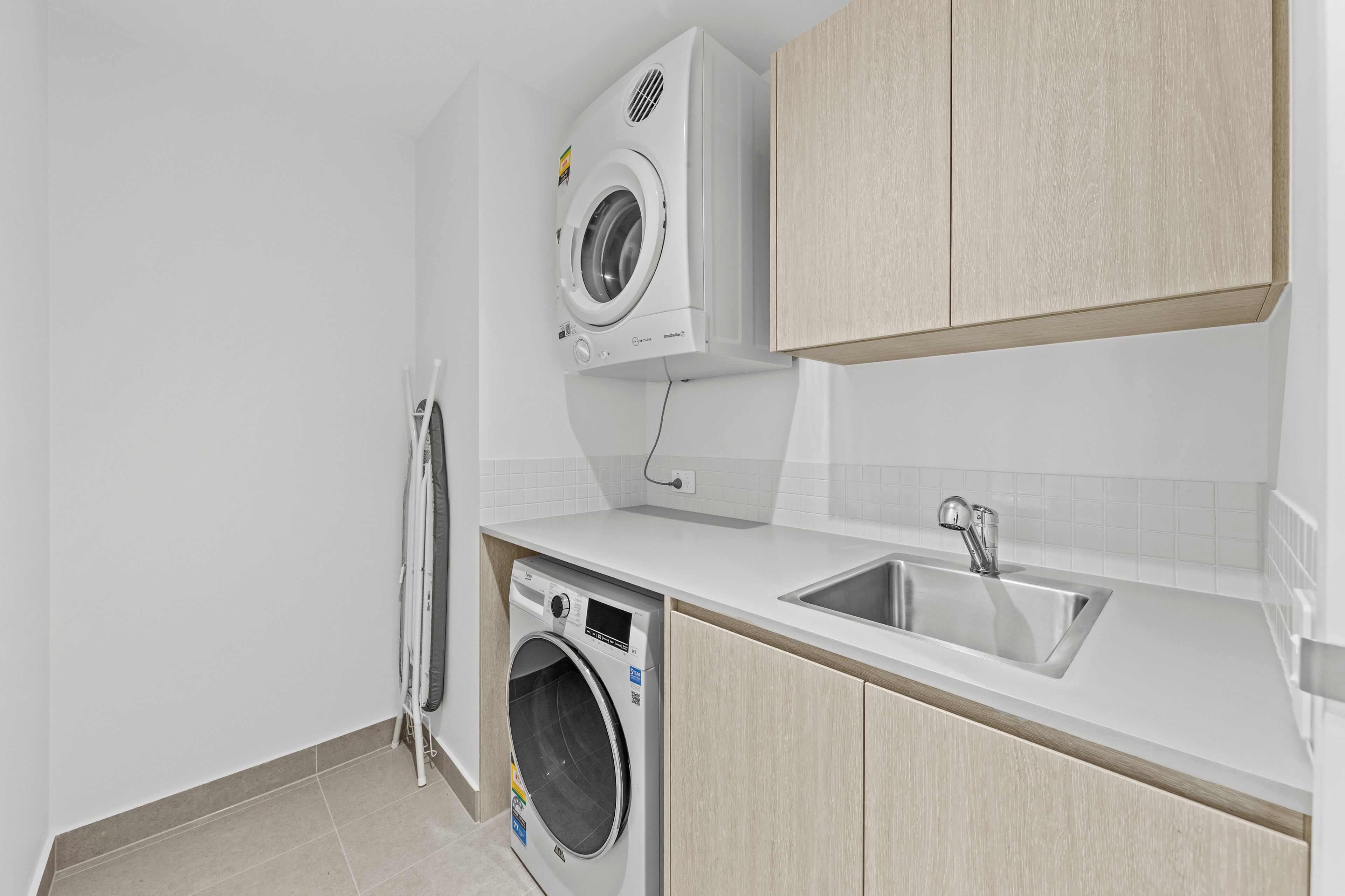 A laundry room with a washing machine, dryer, and sink.