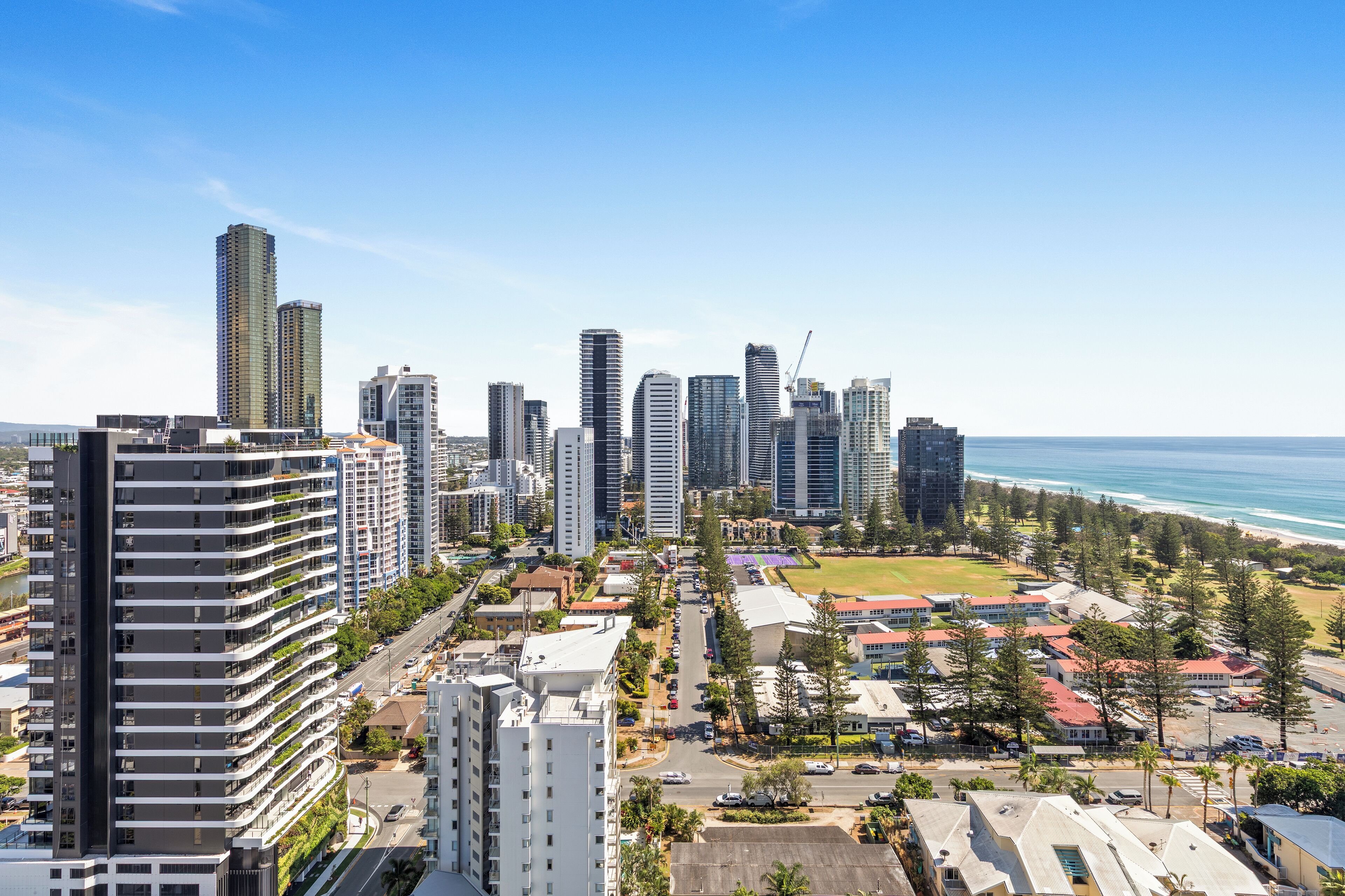 Un quartier urbain composé d’immeubles de grande hauteur, doté d’une architecture moderne, offrant une vue dégagée sur l’océan et comprenant un parc bien entretenu.
