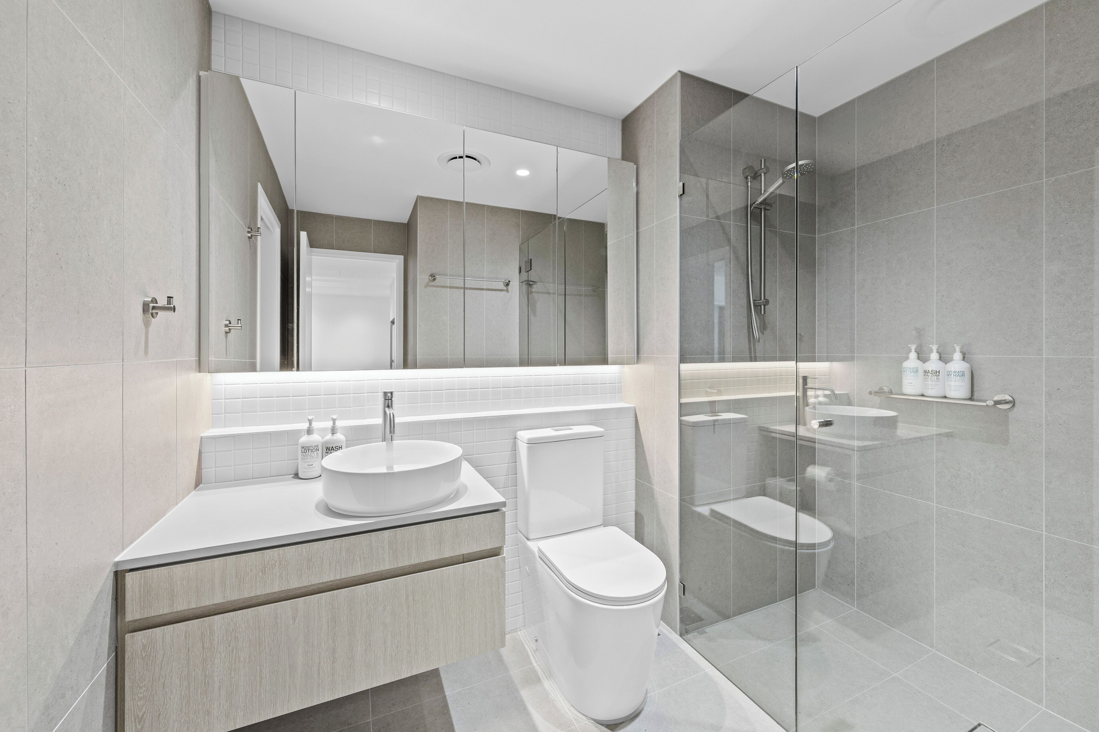 A modern bathroom with a glass-enclosed shower, a white sink, and a toilet.
