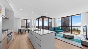 A modern apartment with a kitchen, dining area, and living room with large windows. - Yves Mermaid Beach Apartments by CLLIX (Mermaid Beach)
