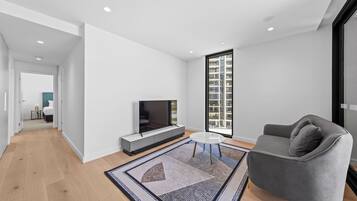 A modern living room with a flat-screen TV, a gray sofa, and a patterned rug.
