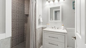A bathroom with a shower, a sink with a mirror, and a towel rack.