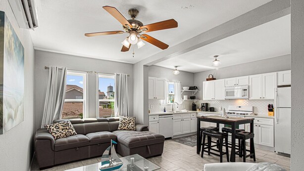 A modern living room with a sofa, a glass coffee table, and a ceiling fan.